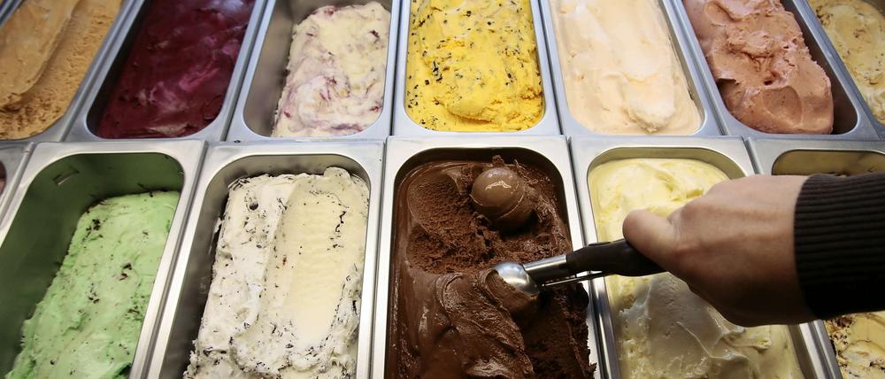 Ein Mensch holt eine Eiskugel aus den Eisbechern.