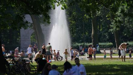 Zahlreiche Menschen suchen bei hochsommerlichen Temperaturen den kühlenden Springbrunnen im Treptower Park auf. 