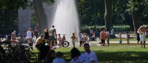 Zahlreiche Menschen suchen bei hochsommerlichen Temperaturen den kühlenden Springbrunnen im Treptower Park auf. 