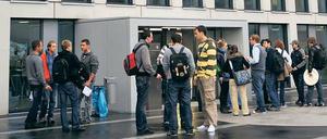 Studierende stehen vor einer Hochschule und unterhalten sich in kleinen Grüppchen.