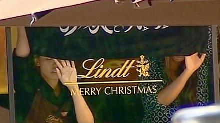 Zwei Geiseln in einem Café in Sydney halten eine Fahne mit arabischer Aufschrift ans Fenster.