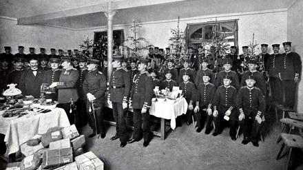 Eine Gruppe von Offizieren und Soldaten hat sich zu Weihnachten vor dem Gabentisch versammelt. 