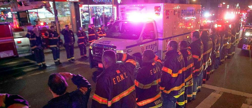 New Yorker Feuerwehrleute salutieren vor einem Krankenwagen, in dem einer der getöteten Polizisten transportiert wird.