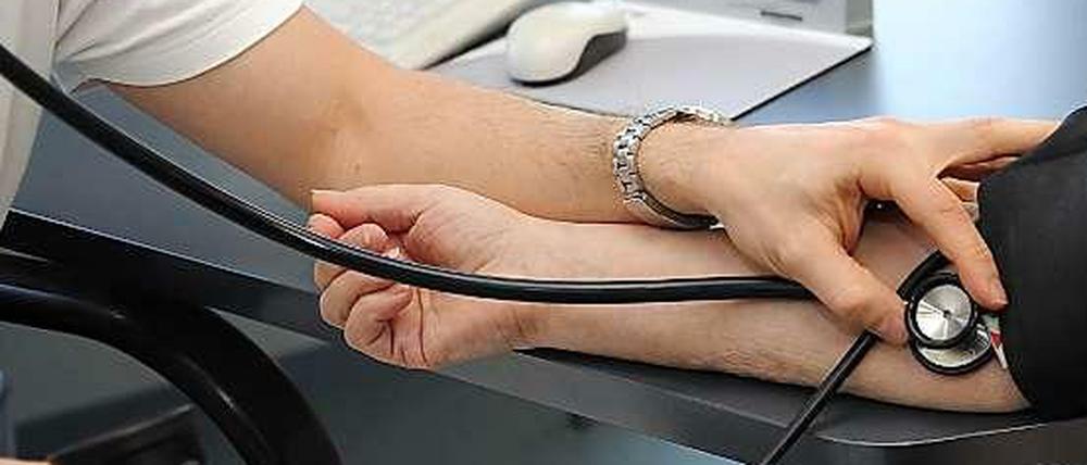 Ein Arzt misst den Blutdruck einer Patientin.