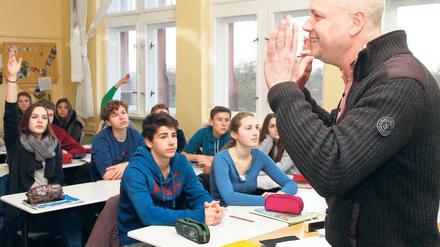 Ein Lehrer steht gestikulierend vor seiner Klasse.