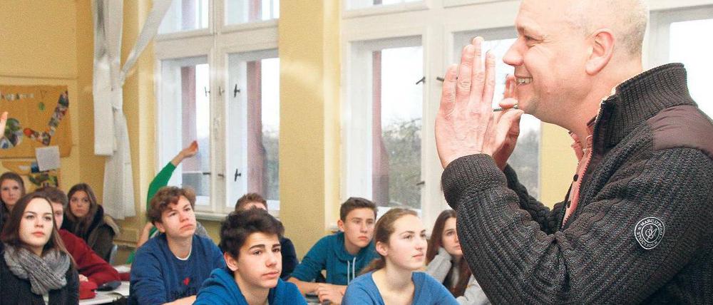 Ein Lehrer steht gestikulierend vor seiner Klasse.