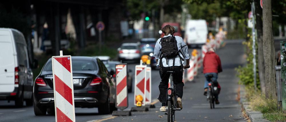 Radfahrer sind auf dem Pop-up-Radweg am Halleschen Ufer unterwegs, während ein Pkw verbotswidrig auf der Fahrbahn daneben parkt.