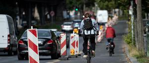 Radfahrer sind auf dem Pop-up-Radweg am Halleschen Ufer unterwegs, während ein Pkw verbotswidrig auf der Fahrbahn daneben parkt.