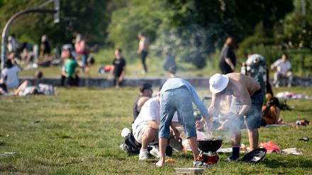 Nicht immer sauber und nie gut für die Luft: Drei Männer grillen bei sonnigen Wetter im Mauerpark.