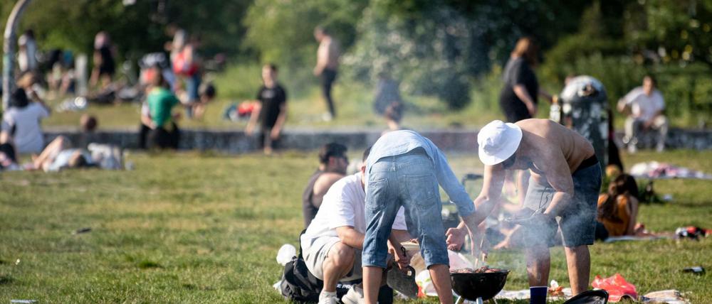 Nicht immer sauber und nie gut für die Luft: Drei Männer grillen bei sonnigen Wetter im Mauerpark.