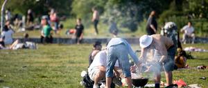 Nicht immer sauber und nie gut für die Luft: Drei Männer grillen bei sonnigen Wetter im Mauerpark.