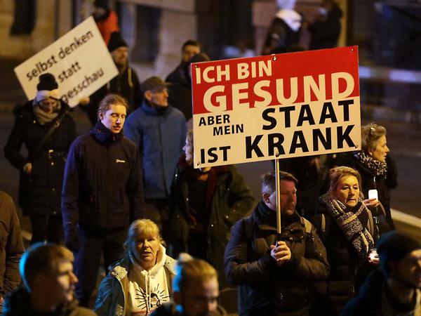 Demonstranten halten ein Schild mit der Aufschrift "Ich bin gesund, aber mein Staat ist krank" hoch.