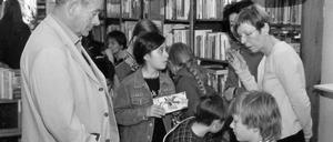 "Wie gut, dass auch viele junge Leute zuhören", schreibt Horst Pillau über die freitäglichen Lesungen im Buchladen Bayerischer Platz. Oder sogar selbst lesen, wie hier der 11-jährige Jakob Beck von dem sich Horst Pillau am Welttag des Buches 2005 hier im Bild ein Buch signieren lässt. Rechts im Bild die Buchhändlerin, Christiane Fritsch-Weith