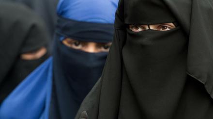 Eine vollverschleierte Frau schaut durch die Schlitze ihres Nikab in Offenbach.