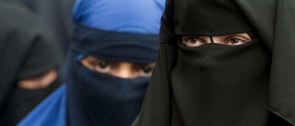Eine vollverschleierte Frau schaut durch die Schlitze ihres Nikab in Offenbach.