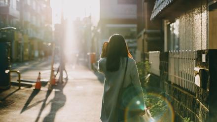 Rear view of woman leaving home to work in the early morning against warm sunlight.