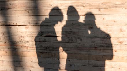 Flüchtlinge zeichnen sich an einer Holzwand am Landesamt für Gesundheit und Soziales (LaGeSo) in Berlin als Schatten ab.