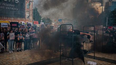 Ein Demonstrant stellt nach, wie Asow-Kämpfer womöglich bei der Explosion des Gefangenenlagers Oleniwka gestorben sind. Die Demonstration wurde von Freunden und Verwandten der Soldaten in Kiew organisiert. 