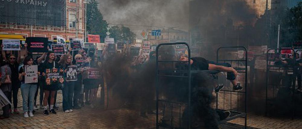 Ein Demonstrant stellt nach, wie Asow-Kämpfer womöglich bei der Explosion des Gefangenenlagers Oleniwka gestorben sind. Die Demonstration wurde von Freunden und Verwandten der Soldaten in Kiew organisiert.