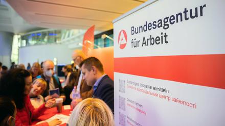 Menschen stehen bei einer Jobmesse für ukrainische Geflüchtete von der IHK Berlin und der Agentur für Arbeit am Stand der Bundesagentur für Arbeit. 