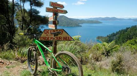 Ein Mountainbike steht an einem Wegweiser vor der Deep Bay, einer von mehreren Buchten des Endeavour Inlets. 