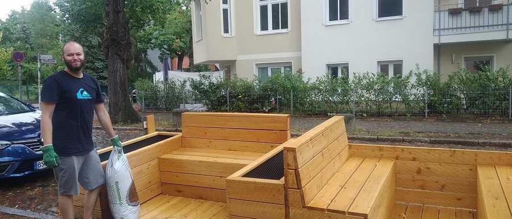 Noch etwas kahl, aber es steht: das erste Lichtenberger Parklet. Alexander Bittner vom Stadtteilzentrum packt schon mal den ersten Sack Erde aus - für die spätere Bepflanzung.