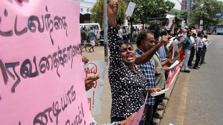 Protestierende stehen mit Plakaten an einer Straße in Colombo.