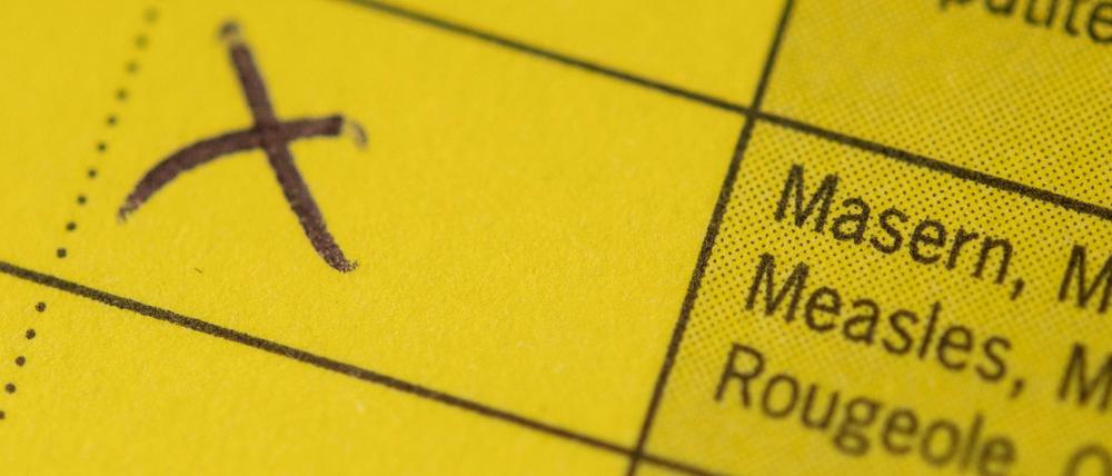 Ein Impfausweis mit bescheinigtem Masernschutz liegt auf einem Tisch.