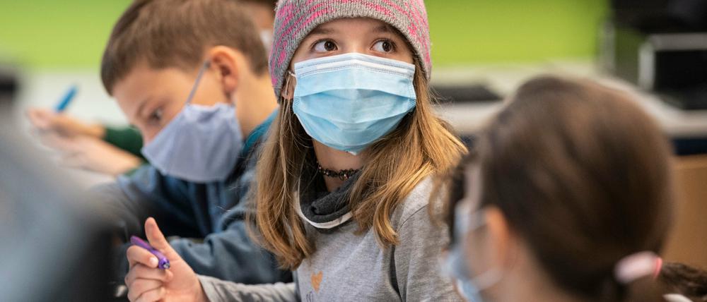 Ein Mädchen trägt im Unterricht Maske und hat eine Mütze auf.