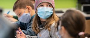 Ein Mädchen trägt im Unterricht Maske und hat eine Mütze auf.