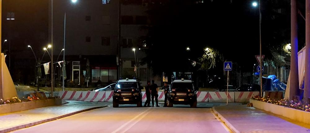 Kosovo, Mitrovica: Polizisten sichern mit ihren Fahrzeugen eine Brücke, während in der Stadt Sirenenalarm zu hören ist.