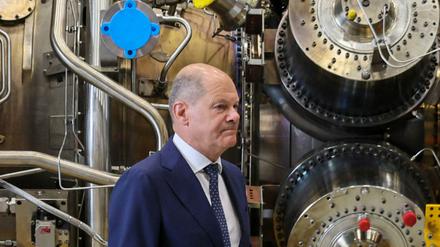 Bundeskanzler Olaf Scholz steht neben einer Gasturbine.
