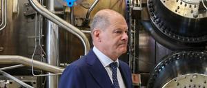 Bundeskanzler Olaf Scholz steht neben einer Gasturbine.