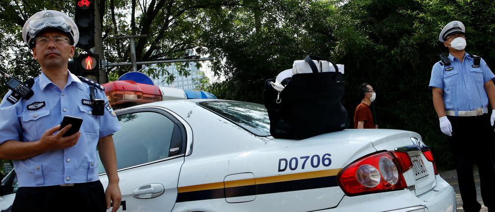 Chinesische Polizeibeamte stehen neben einem Einsatzfahrzeug (Symbolbild).