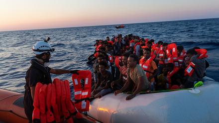 Die Besatzung der Sea-Watch 3 verteilt Rettungswesten an Menschen in einem Schlauchboot.