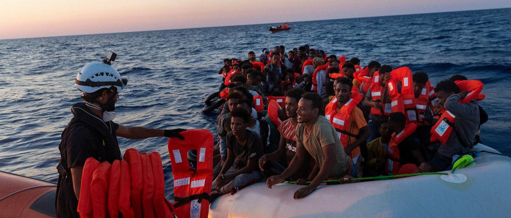 Die Besatzung der Sea-Watch 3 verteilt Rettungswesten an Menschen in einem Schlauchboot.