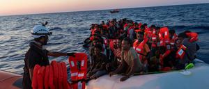 Die Besatzung der Sea-Watch 3 verteilt Rettungswesten an Menschen in einem Schlauchboot.