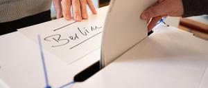 Eine Frau gibt in einem Wahllokal Wahlzettel für die Wahl des Abgeordnetenhauses und den Volksentscheid in Berlin ab.