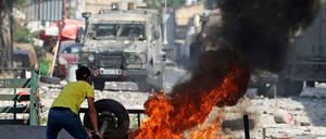 Ein palästinensischer Demonstrant wirft einen Reifen in ein Feuer.