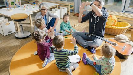 Kinder und Erzieher musizieren (Symbolbild).