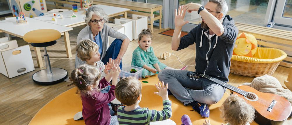 Kinder und Erzieher musizieren (Symbolbild).