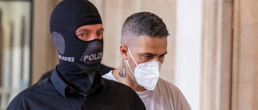 08.08.2022, Berlin: Anis Mohamed Youssef Ferchichi (r), bekannt unter dem Künstlernamen Bushido, kommt in Begleitung von Polizeibeamten zu Beginn der Verhandlung im Prozess gegen den Chef eines bekannten arabischstämmigen Clans und drei seiner Brüder in einen Gerichtssaal. Der Clanchef und seine Brüder stehen unter anderem wegen schwerer räuberischer Erpressung, Freiheitsberaubung und gefährlicher Körperverletzung vor Gericht.