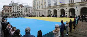 Einwohner von Lwiw enthüllen vor dem Rathaus am Rynok Platz die ukrainische Flagge. Anlass war im März 2021 der Jahrestag der Nationalhymne des Landes.