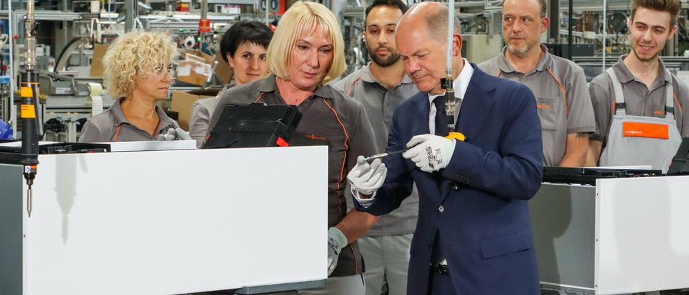 Bundeskanzler Olaf Scholz (SPD) schraubt unter Anleitung einer Viessmann-Mitarbeiterin die letzte Schraube in eine Wärmepumpe.