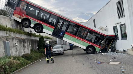 Der hintere Teil eines Busses hängt an einer Mauer, der vordere Teil landete in der Fassade eines Discounters.
