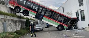 Der hintere Teil eines Busses hängt an einer Mauer, der vordere Teil landete in der Fassade eines Discounters.