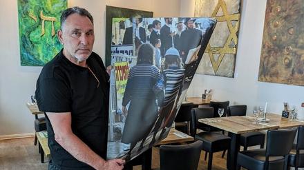 Der Künstler und sein Bild. Rafael Herlich zeigt das beschädigte Foto mit einer Szene aus Jerusalem.