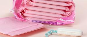 Damenbinden und ein Tampon liegen auf einem Tisch.