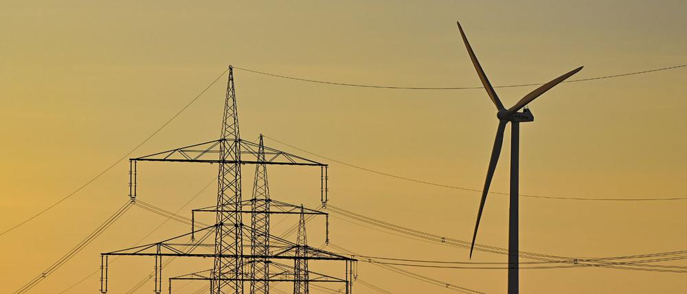 Eine Windenergieanlage steht hinter Hochspannungsmasten von mehreren Stomleitungen. Für Haushalte in Deutschland wird der Strom nach Beobachtungen von Vergleichsportalen deutlich teurer.