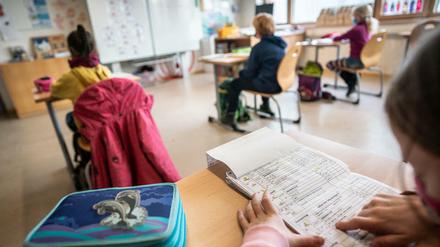 Schulkinder sitzen in einem Klassenraum an ihren Tischen. (Symbolbild)